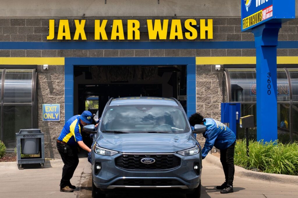 Jax Kar Wash staff cleaning vehicle at entrance bay
