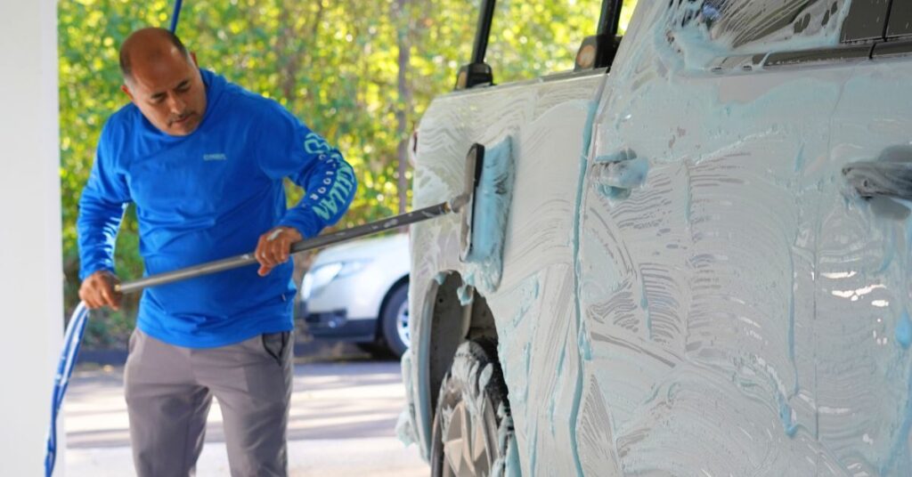 Worker scrubbing truck with foam during car wash service