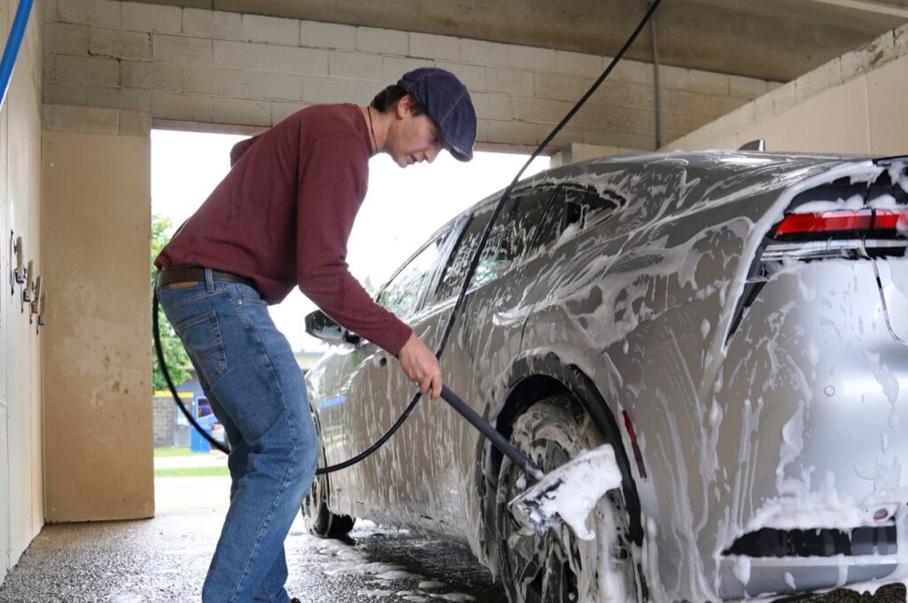 Man scrubbing soapy car wheel at self-serve wash