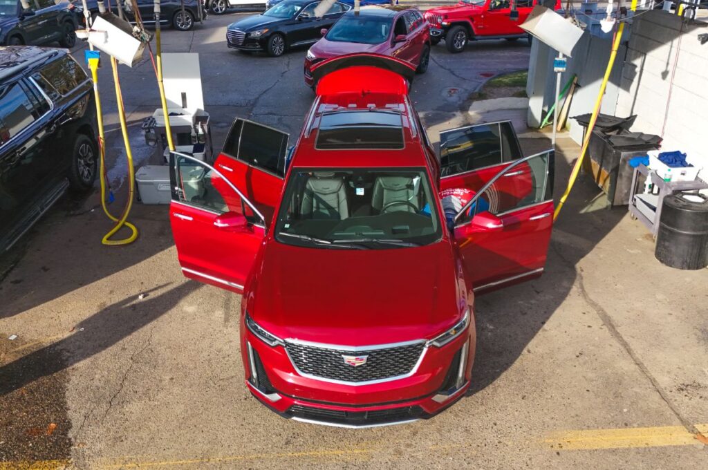 Red car being cleaned at self-service car wash.