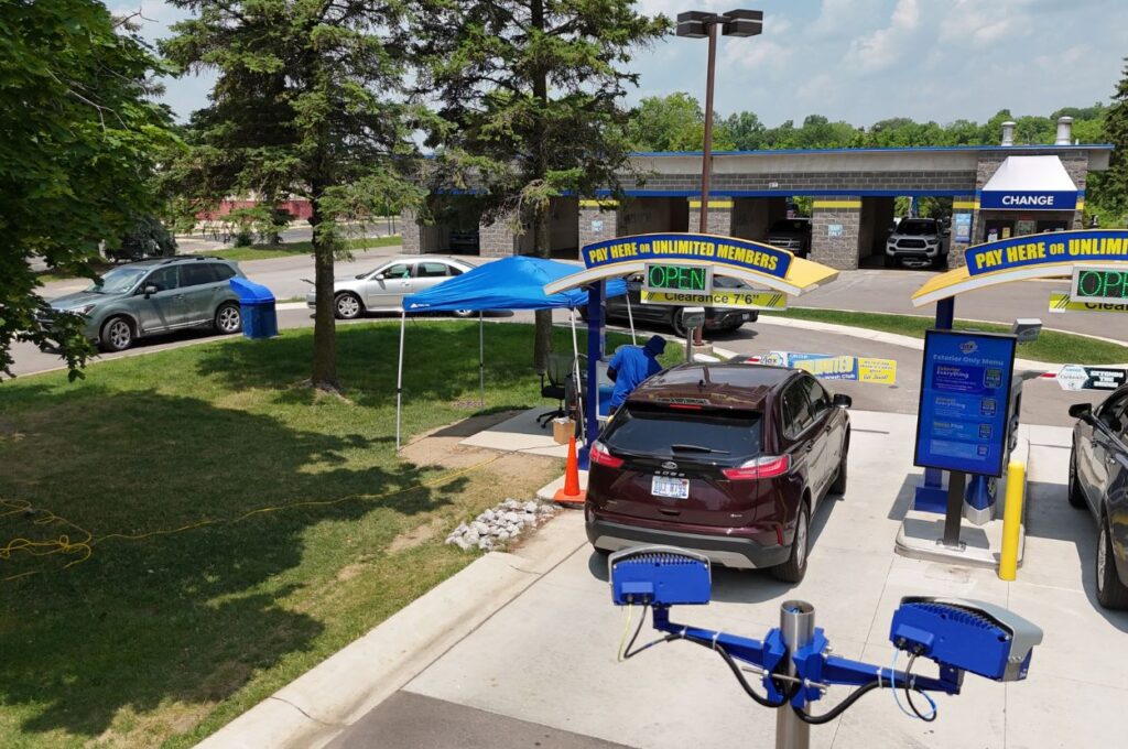 Car at payment kiosk with staff assisting driver.