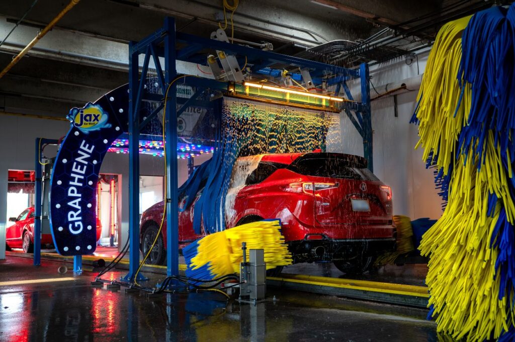 Red car receives graphene treatment in automatic wash.