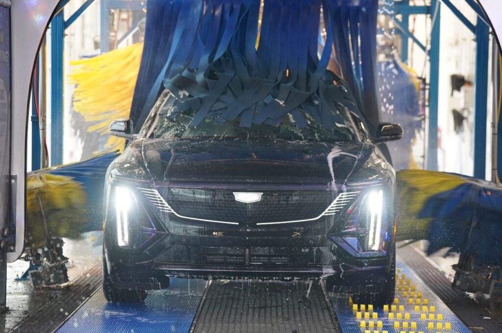 Black vehicle moves through an automatic car wash.
