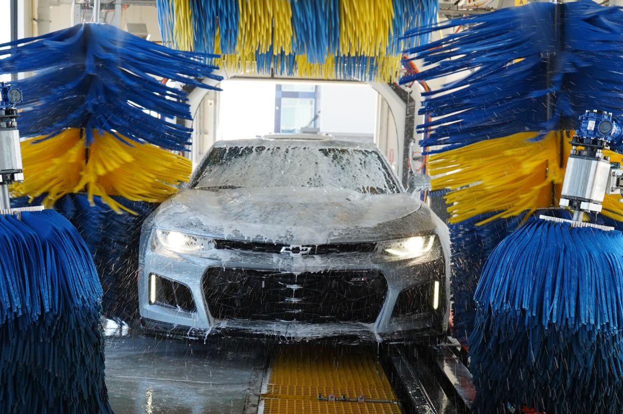 Soapy car passes through blue and yellow brushes.