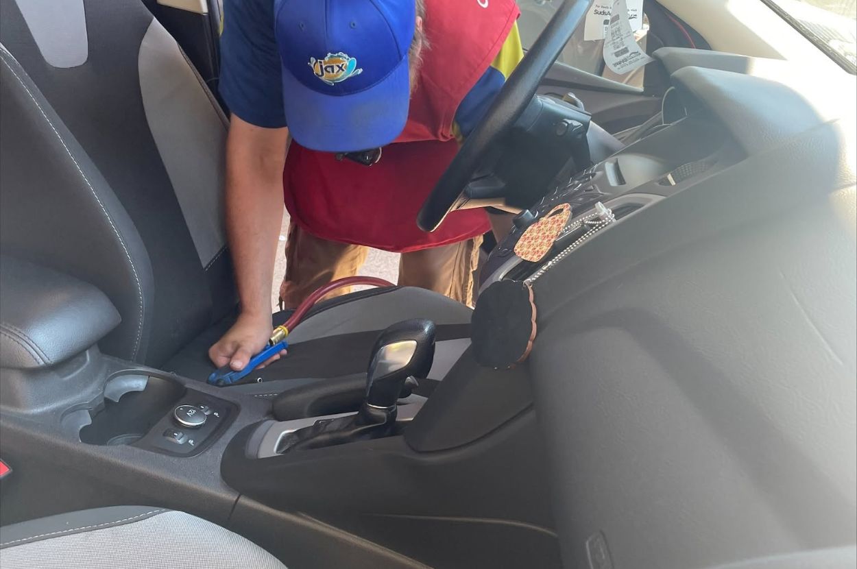 Technician uses compressed air to detail car interior.
