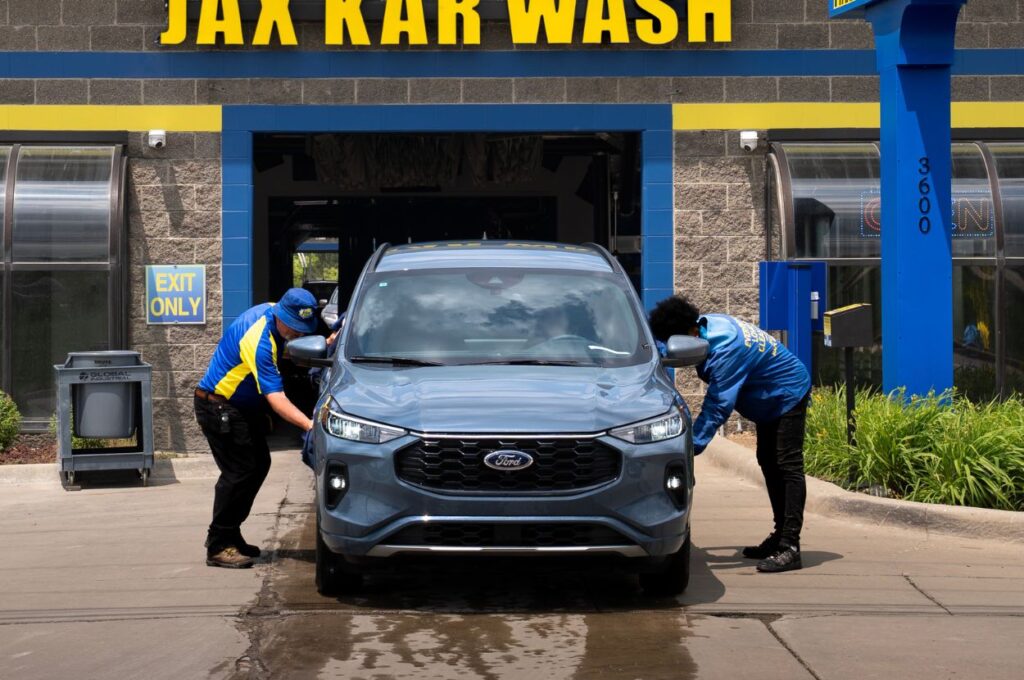 Two technicians dry a car at car wash.