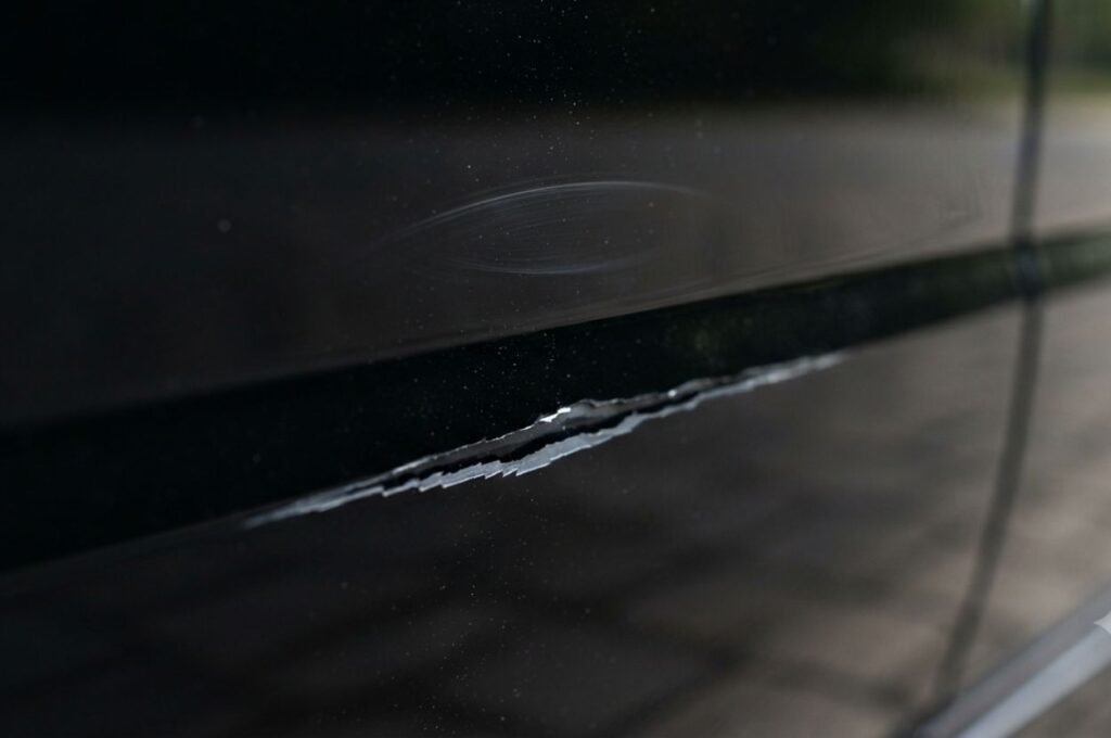 Car scratches running across a glossy black vehicle door