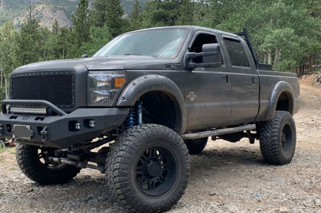Lifted dark pickup truck parked on mountain trail.