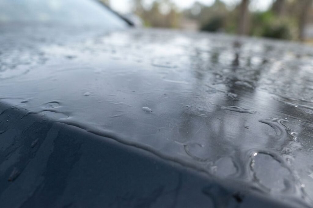 Close-up of the hood of a dark metallic vehicle after the wax has worn away